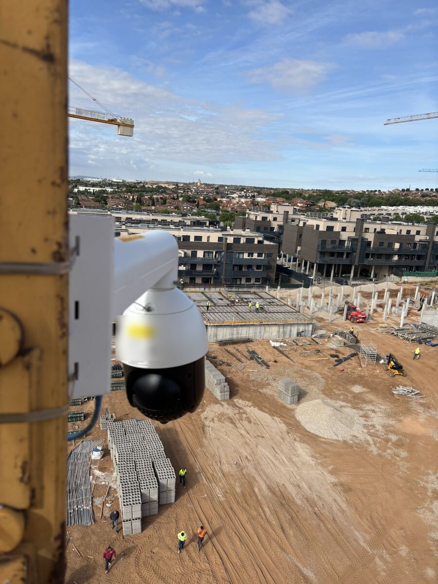 Dome camera fixed to a yellow crane mast with the whole plot visible below