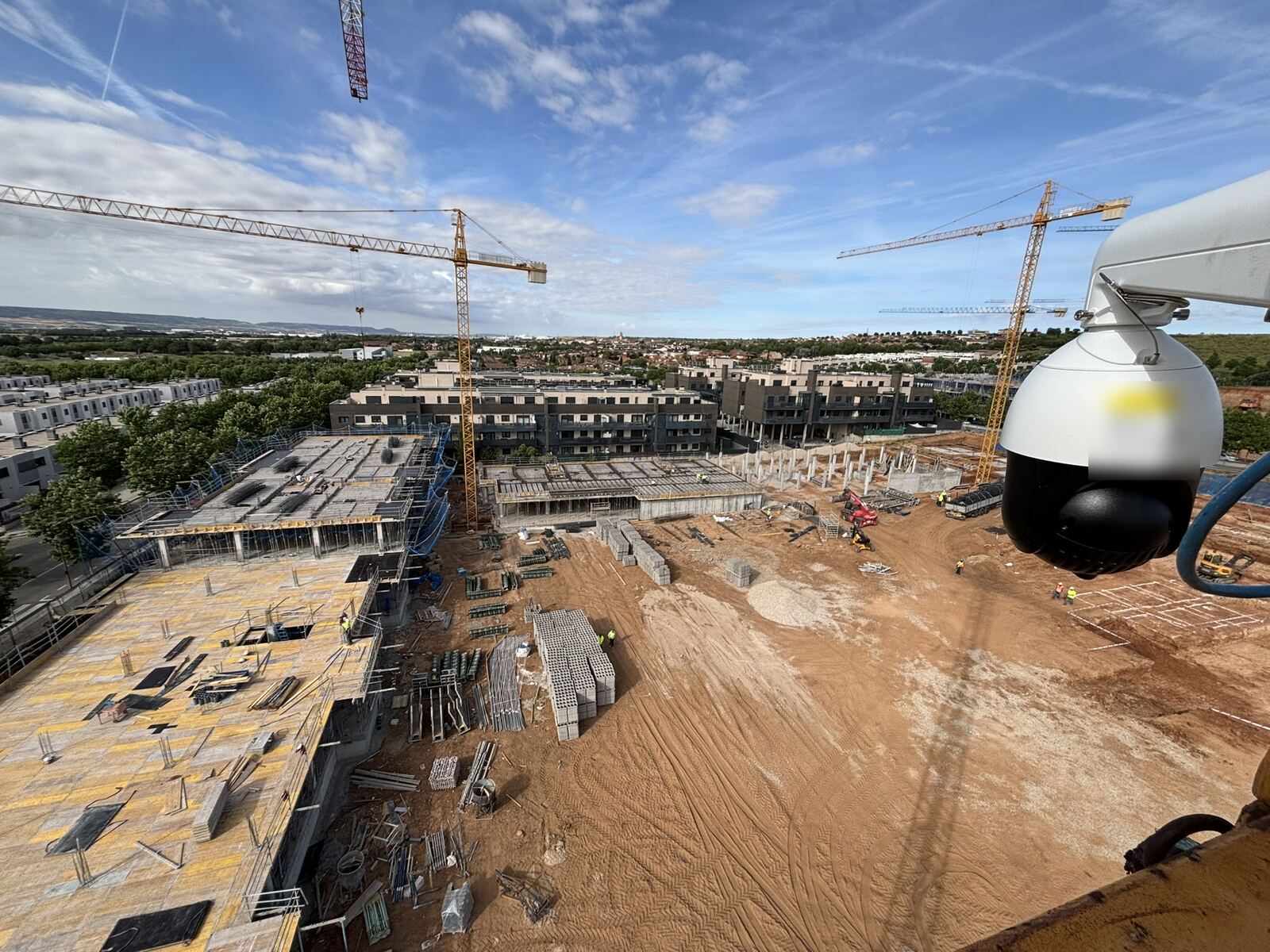 A PTZ camera mounted on a tower crane, looking down over a housing development under construction
